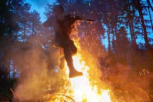 soldato nel azione a notte salto al di sopra di fuoco foto