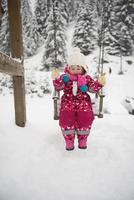 poco ragazza a nevoso inverno giorno swing nel parco foto