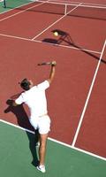 il giovane gioca a tennis all'aperto foto