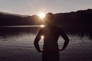 atleta di triathlon che inizia l'allenamento di nuoto sul lago foto