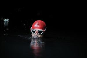 autentico nuotatore triatleta che fa una pausa durante un duro allenamento notturno foto