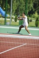 il giovane gioca a tennis all'aperto foto