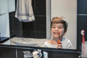 poco ragazzo spazzolatura denti nel il mattina. foto