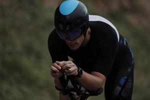 atleta di triathlon in sella a una bicicletta vestita di nero foto