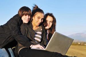 gruppo di adolescenti Lavorando su il computer portatile all'aperto foto