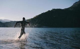 atleta di triathlon che inizia l'allenamento di nuoto sul lago foto