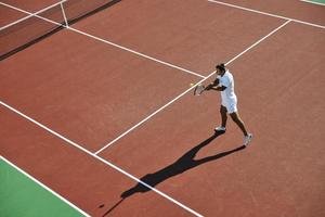 il giovane gioca a tennis all'aperto foto