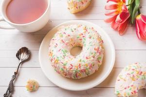 tazza di tè e ciambelle, fiori tulipani su bianca tavolo con copia spazio. foto