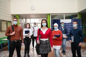 studenti gruppo a Università a piedi e indossare viso maschera foto