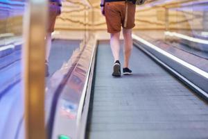 giovane uomo va giù su in movimento passerella nel shopping centro foto