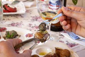 un' donna mangiare delizioso lumache con Limone su il tavolo foto