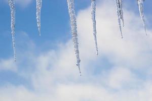 ghiaccioli sospeso su tetto a inverno. naturale ghiaccio formazione di ghiaccio cristalli sospeso su tetto bordo a inverno foto