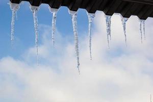 ghiaccioli sospeso su tetto a inverno. naturale ghiaccio formazione di ghiaccio cristalli sospeso su tetto bordo a inverno foto
