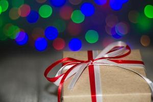 Natale regalo scatola contro bokeh sfondo. vacanza saluto carta foto