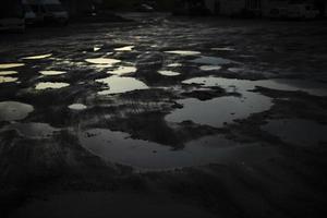 grande pozzanghera nel scuro. riflessione di leggero nel pozzanghera. cattivo strada nel Russia. foto