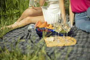 picnic nel estate nel parco. cibo su sfondo di ragazze. Champagne occhiali. dettagli di riposo nel parco. cibo su strada. foto