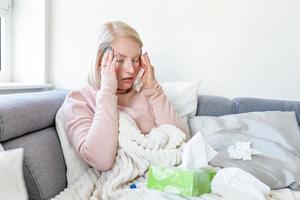 malato donna con mal di testa seduta sotto il lenzuolo. malato donna con di stagione infezioni, influenza, allergia dire bugie nel letto. malato donna coperto con un' coperta dire bugie nel letto con alto febbre e un' influenza, riposo. foto