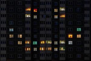 piatto notte panorama di multicolore Sorridi viso leggero nel finestre di multipiano edifici foto