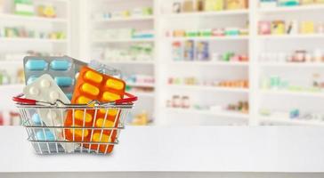 pacchetto di pillole medicinali nel carrello con gli scaffali della farmacia della farmacia sfocano lo sfondo foto