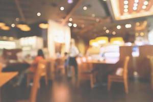 l'interno del ristorante con il cliente e il tavolo in legno sfocano lo sfondo astratto con luce bokeh foto