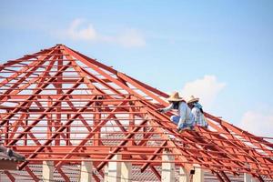 lavoratori del saldatore che installano la struttura del telaio in acciaio del tetto della casa in un cantiere edile foto