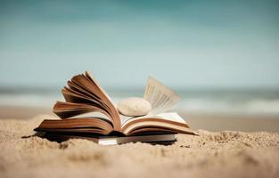 lettura libro all'aperto nel estate concetto. ha aperto libro su il spiaggia sabbia nel davanti di il mare su soleggiato giorno. stile di vita su vacanza foto