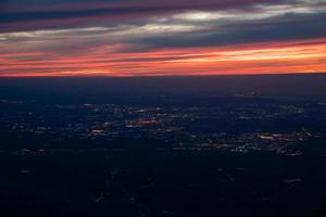 dal crepuscolo alla notte dall'aereo a reazione vista rosso arancio blu cielo con la luce della città della tailandia sotto foto