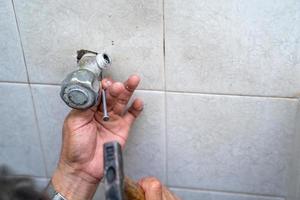 l'uomo asiatico cerca di riparare e riparare il tubo della doccia nel vecchio bagno. foto