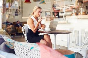 donna d'affari seduto a un tavolo nella piccola caffetteria foto