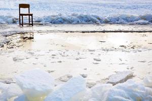 legato al ghiaccio sedia vicino ghiaccio buco nel congelato lago foto