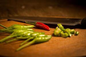 il giro legna chopping taglio tavola. chili peperoni verde e rosso. coltello foto