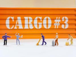 gruppo di miniatura persone lavoratori figura con carico contenitore a magazzino, industriale e logistica concetto foto