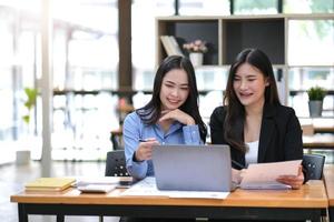 due giovani donne d'affari asiatiche discutono con la presentazione di una nuova idea di progetto di avvio, analizzano le statistiche finanziarie e di pianificazione e il mercato degli investimenti in ufficio. foto