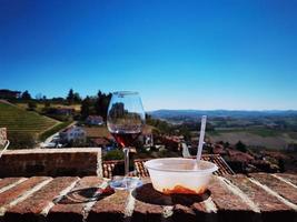 bicchiere di vino e piatto di ravioli con un' Visualizza di il piemontese langhe di monforte d'alba foto