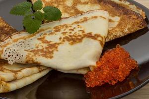 Pancakes con rosso caviale su il piatto e di legno sfondo foto