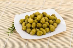 verde olive su il piatto e di legno sfondo foto