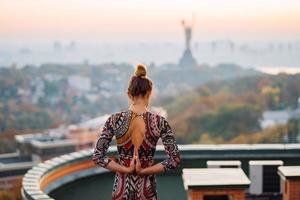 donna fare yoga su il tetto di un' grattacielo nel grande città. foto