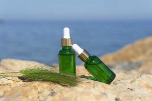 cosmetico contagocce bottiglie In piedi su pietre a il mare con il mare su il sfondo foto