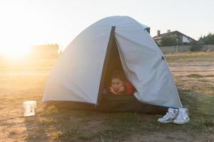 giovane donna sbirciando su di il tenda con solo sua testa attaccare su foto