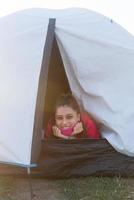 giovane donna sbirciando su di il tenda con solo sua testa attaccare su foto