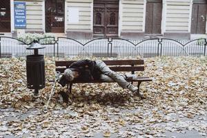 senza casa addormentato su il panchine nel il autunno parco foto