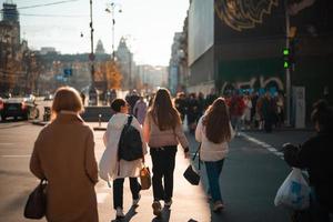 molte di persone attraversamento il strada a il traffico luci. foto