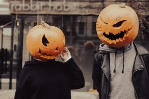 un' tipo e un' ragazza con un' zucca teste in posa su il strada foto