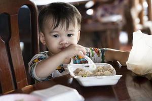 carino poco ragazzo è mangiare cibo felicemente. bambino felicemente mangia prima colazione. foto