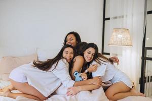 positivo giovane ragazze donne amici in casa su letto a il gallina festa a casa. foto