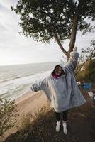 giovane donna su freddo autunno riva del mare in posa a telecamera foto