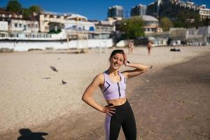 bellissimo donna nel un' pubblico spiaggia dopo formazione con sportivo Guarda foto