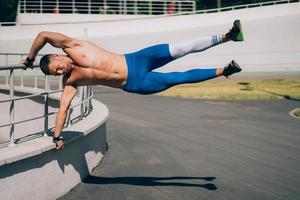 giovane atletico uomo esegue ginnastica elementi - umano bandiera. foto