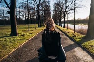 ritratto di un' brunetta ragazza avendo divertimento nel un' parco nel il raggi di il luminosa sole. foto