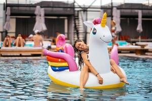 donna su gonfiabile unicorno giocattolo materasso galleggiante nel piscina. foto